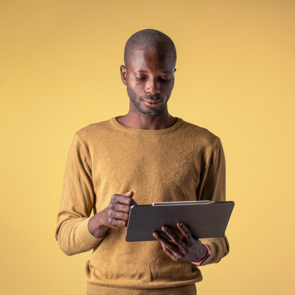 Young African American Man Using Tablet - Casual Indoor Tech Use on Yellow Background